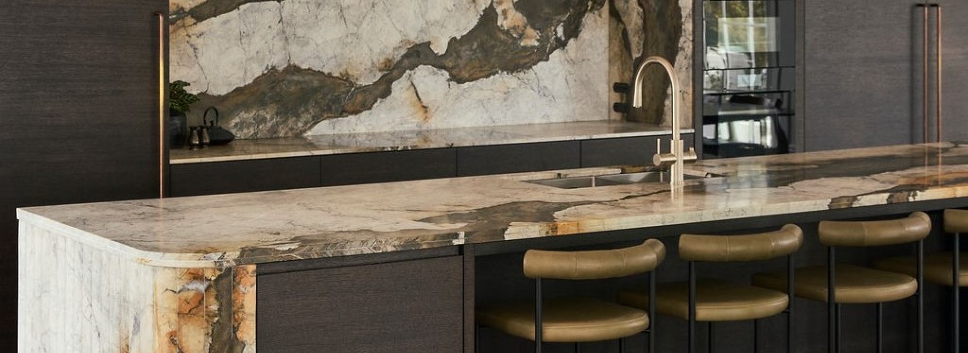 Iron white Calacatta marble kitchen island with multifaceted waterfall end and splashback and cladded rangehood